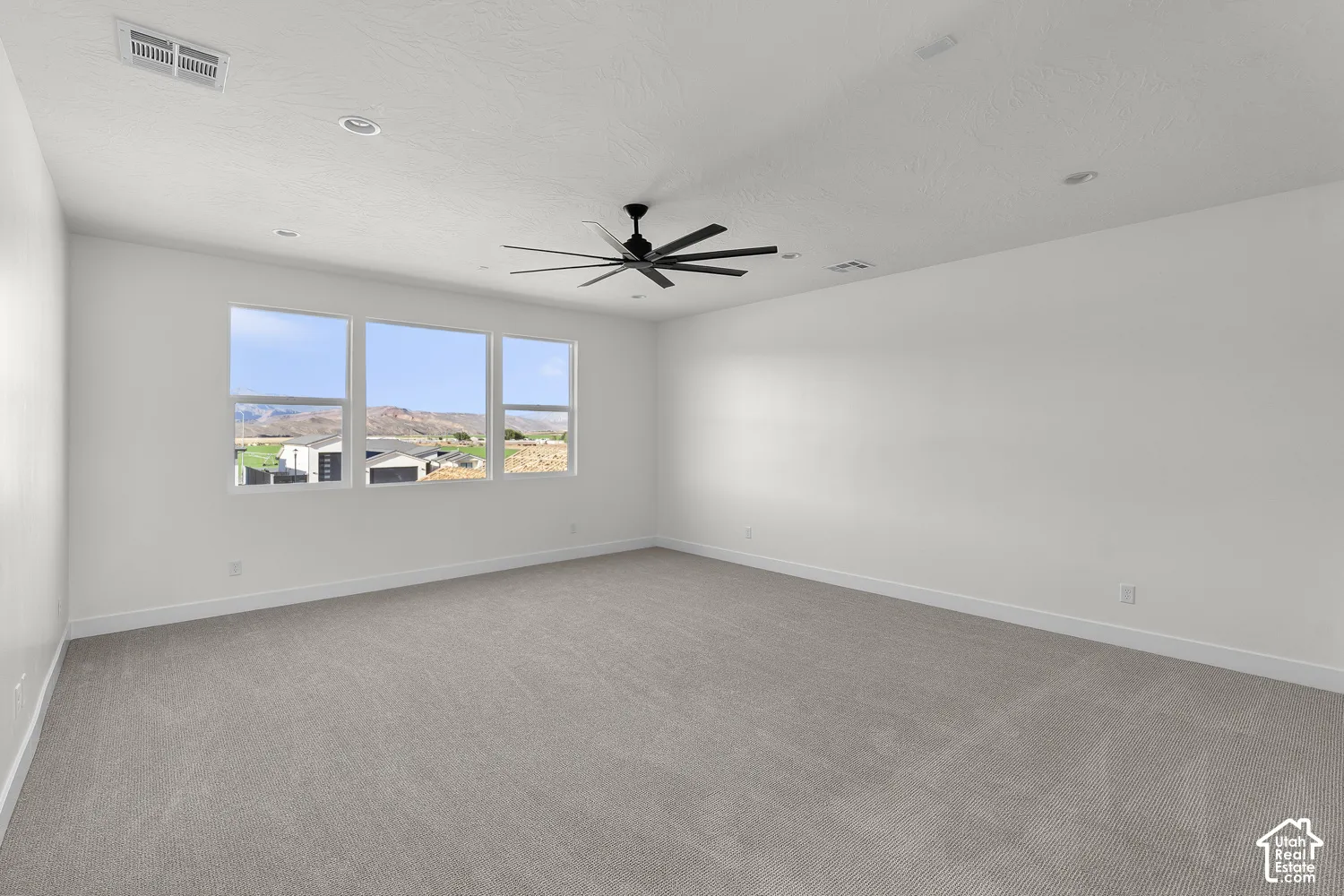 Spacious room featuring three large windows, recessed lighting, and a ceiling fan