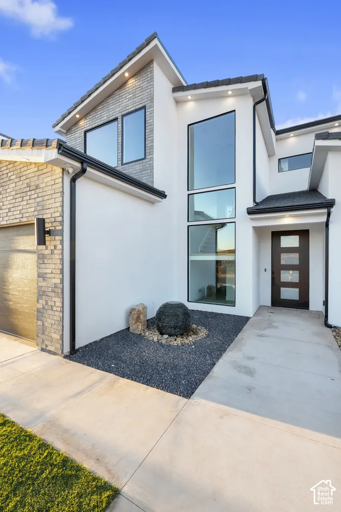 Contemporary exterior with a smooth stucco finish, multi-pane windows, and a dark wood-finish entry door