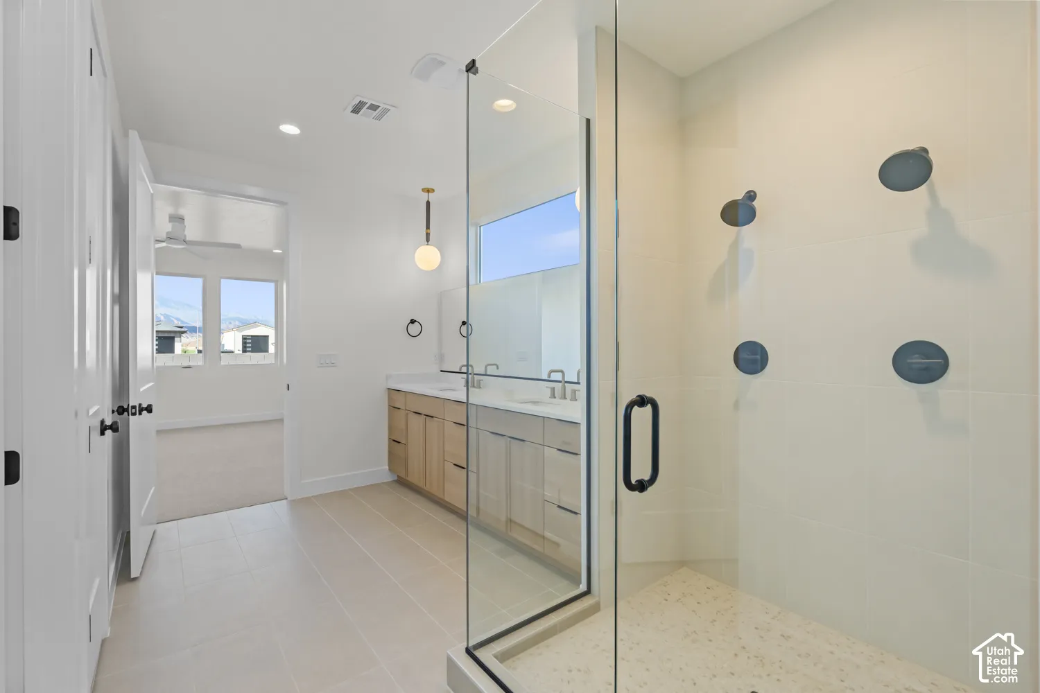 Large glass-enclosed shower with multiple matte black shower heads