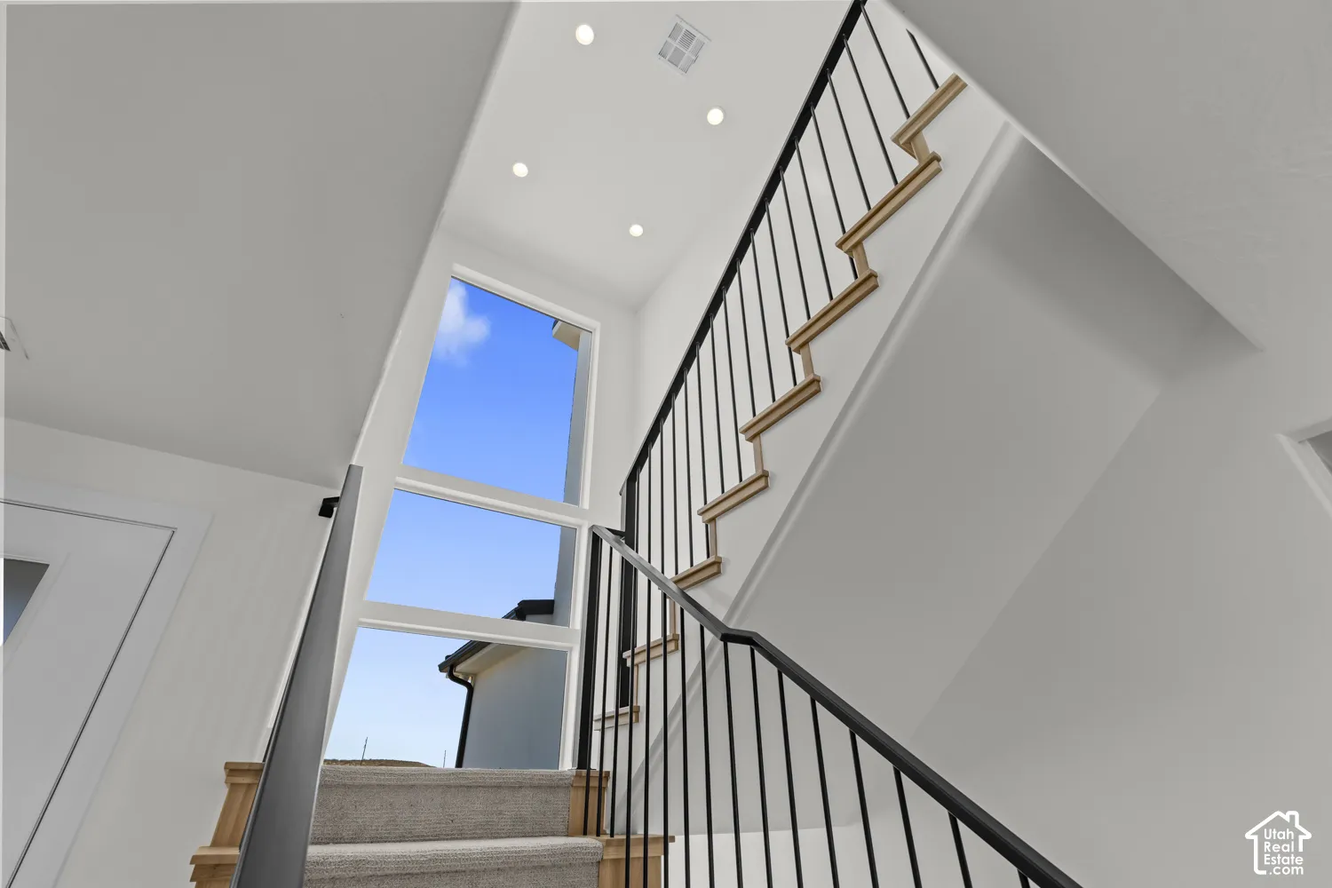 Staircase featuring wood-finish treads, carpeted risers, and black metal railings
