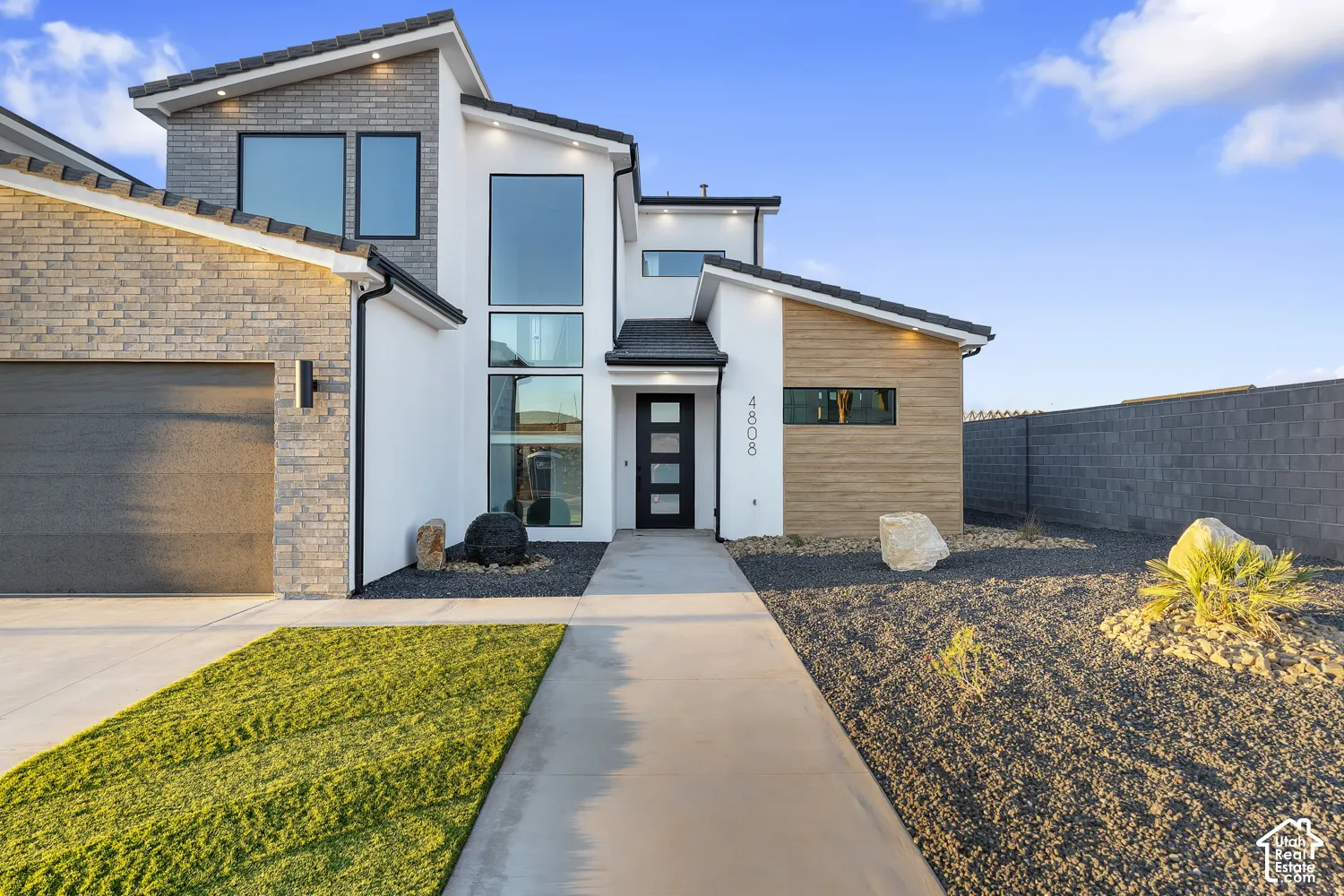 Modern architectural home featuring a clean-lined facade with white exterior cladding, natural wood siding accents, and expansive glazing