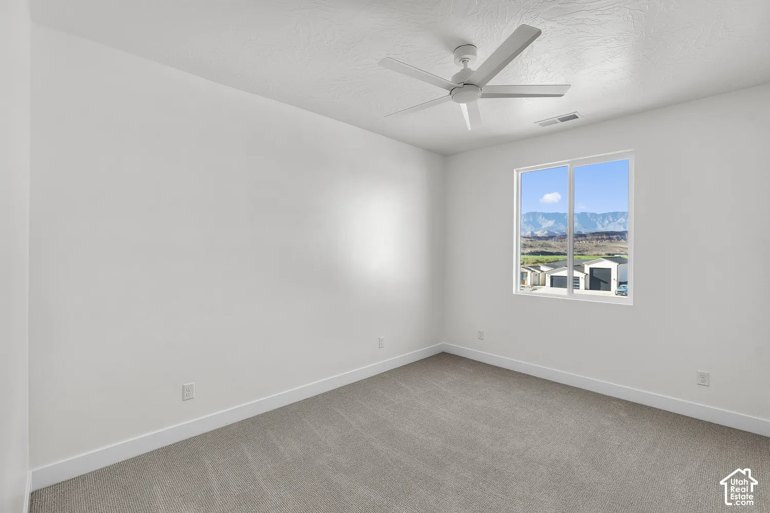 Neutral wall paint, ceiling fan, expansive window, carpeted flooring, and white trim