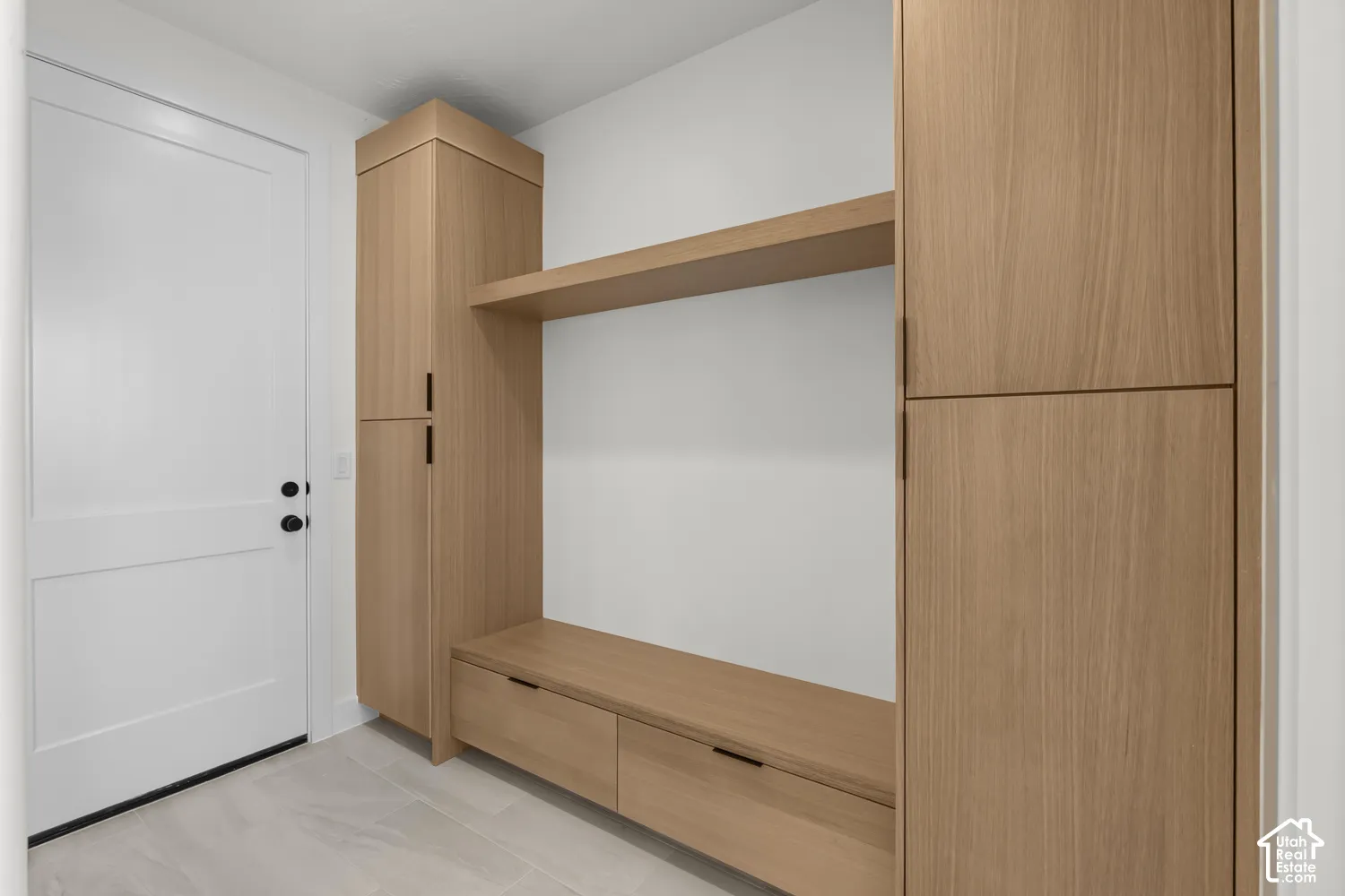 Built-in wood-finish cabinetry featuring open shelving and integrated bench seating with drawer storage, complemented by a white paneled door