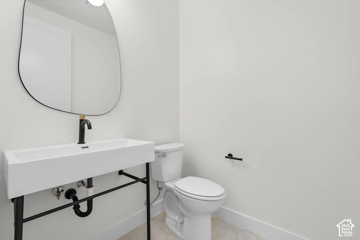 Modern vanity with a rectangular basin, matte black faucet, and an organically shaped mirror