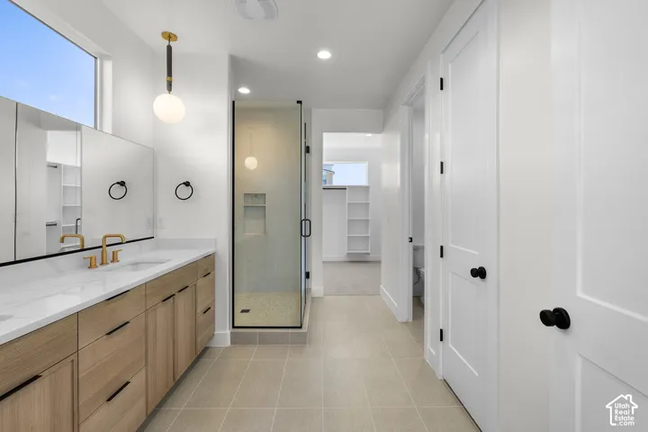 Double vanity with light wood-finish cabinetry, gold-finish hardware, and a framed mirror