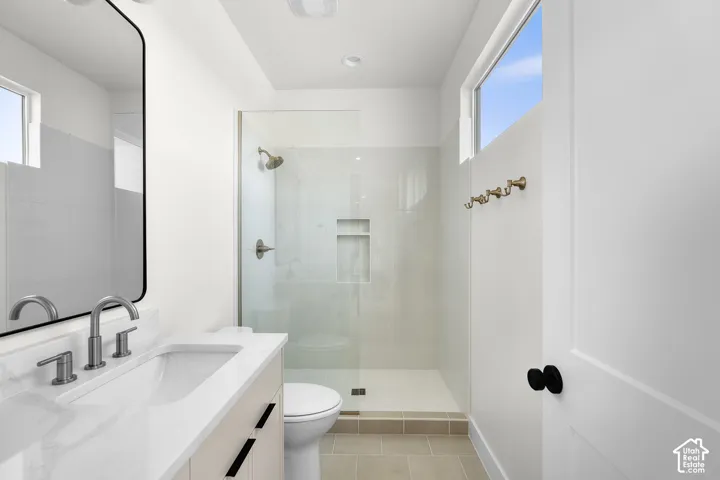 Bathroom featuring a floating vanity with a white countertop and rectangular sink, a glass-enclosed shower with a built-in niche, and a transom window