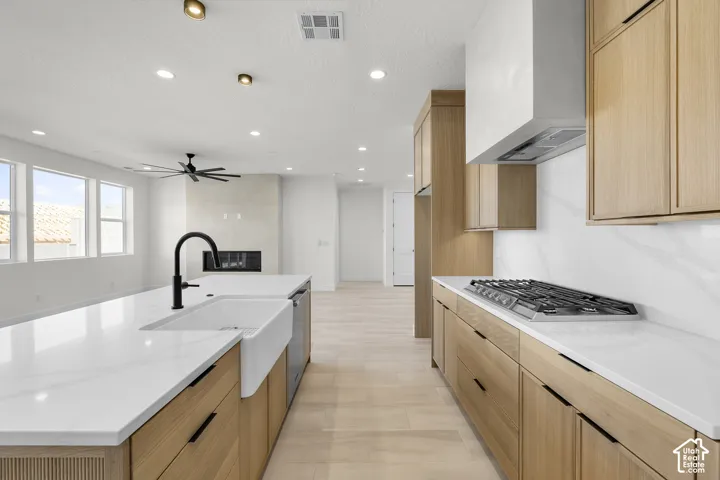Kitchen with wood-finish cabinetry, white countertops, and an undermount farmhouse sink with a gooseneck faucet