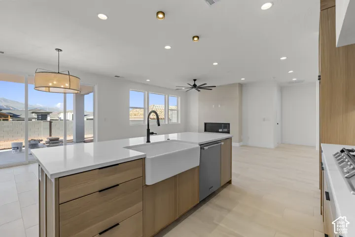 Kitchen island with a farmhouse sink and matte black faucet, integrated dishwasher, and light wood-finish cabinetry