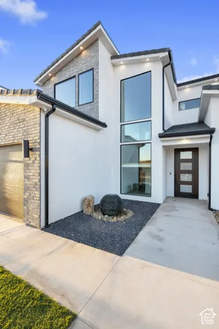 Contemporary exterior with a smooth stucco finish, multi-pane windows, and a dark wood-finish entry door