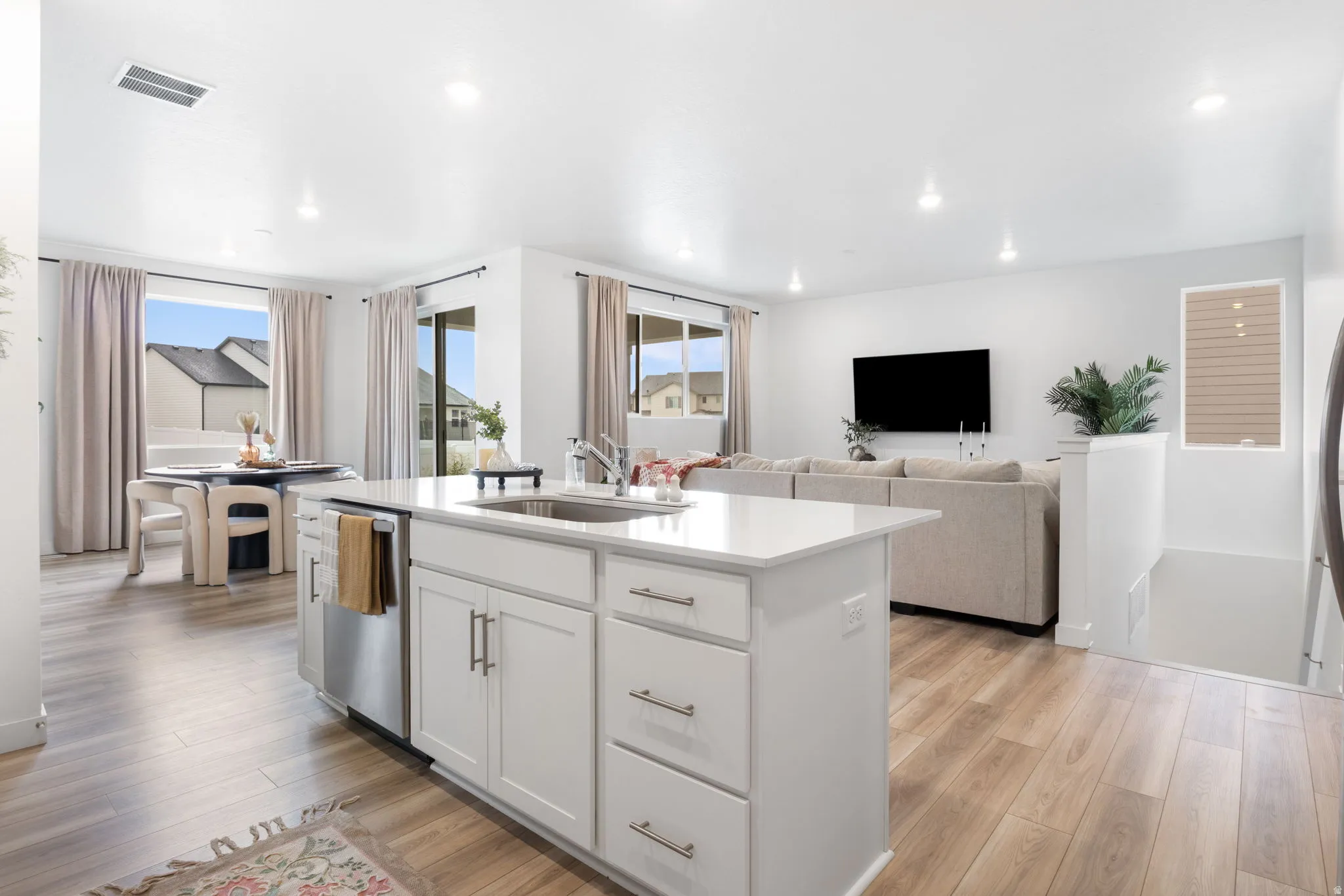 Open-concept living space featuring LVP flooring, recessed lighting, and large windows