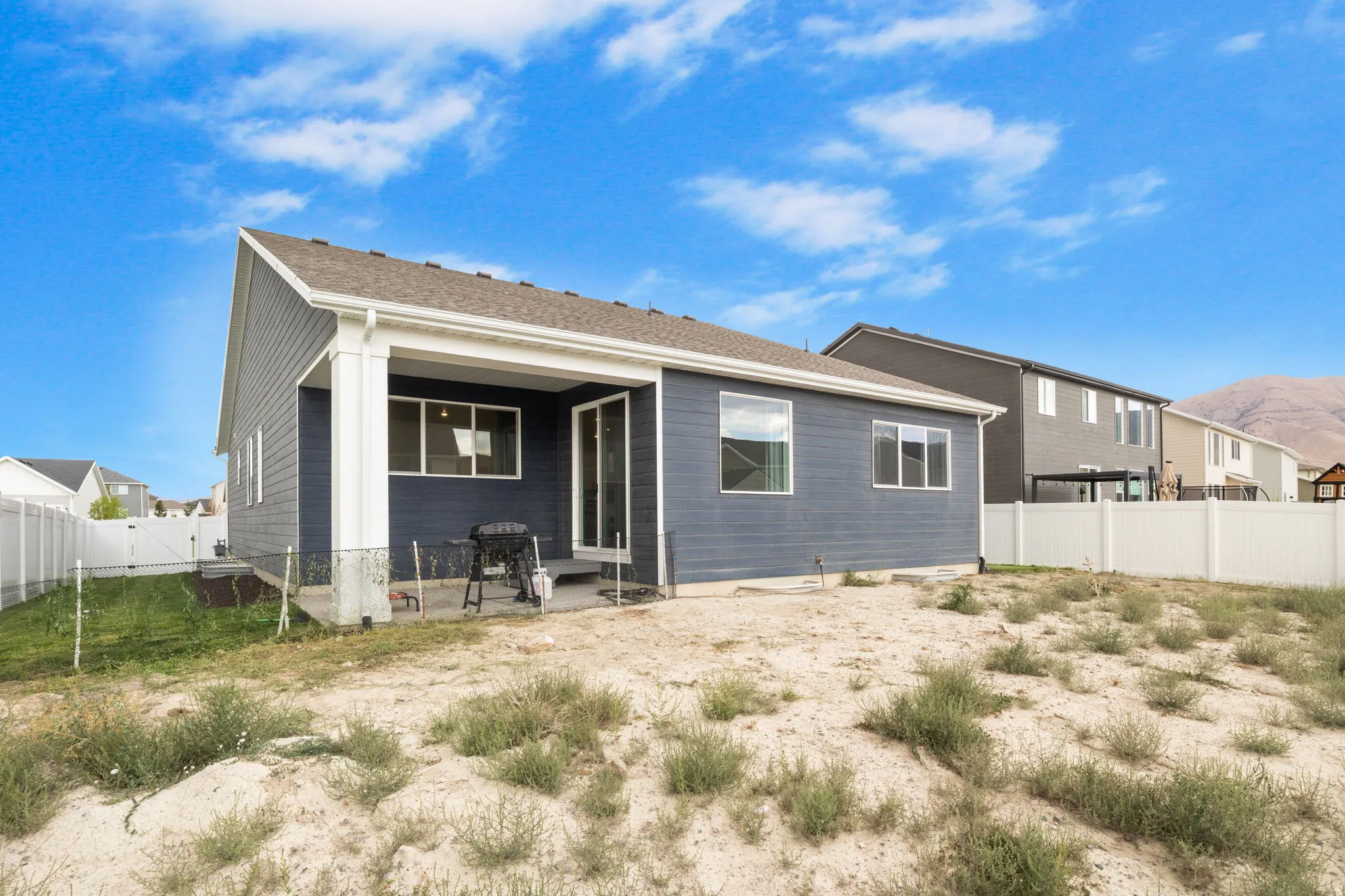 Covered outdoor patio with a sliding glass door, multiple windows, and a fully fenced yard.