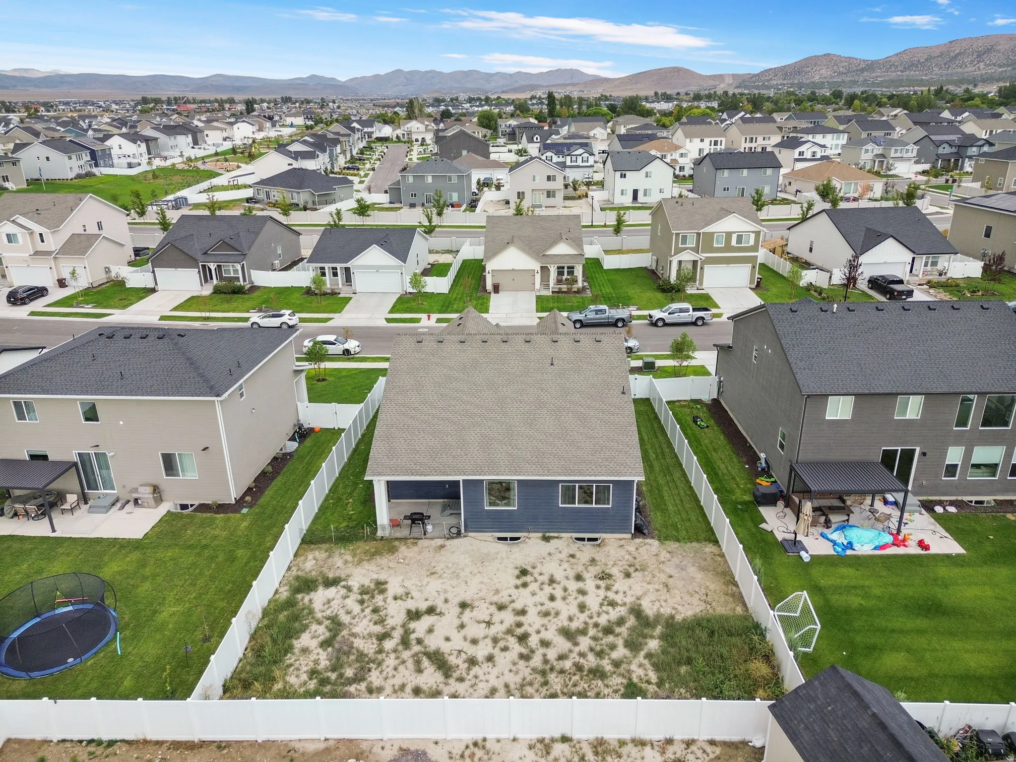 Expansive backyard space, white privacy fencing, mountain backdrop, residential street, and a community setting