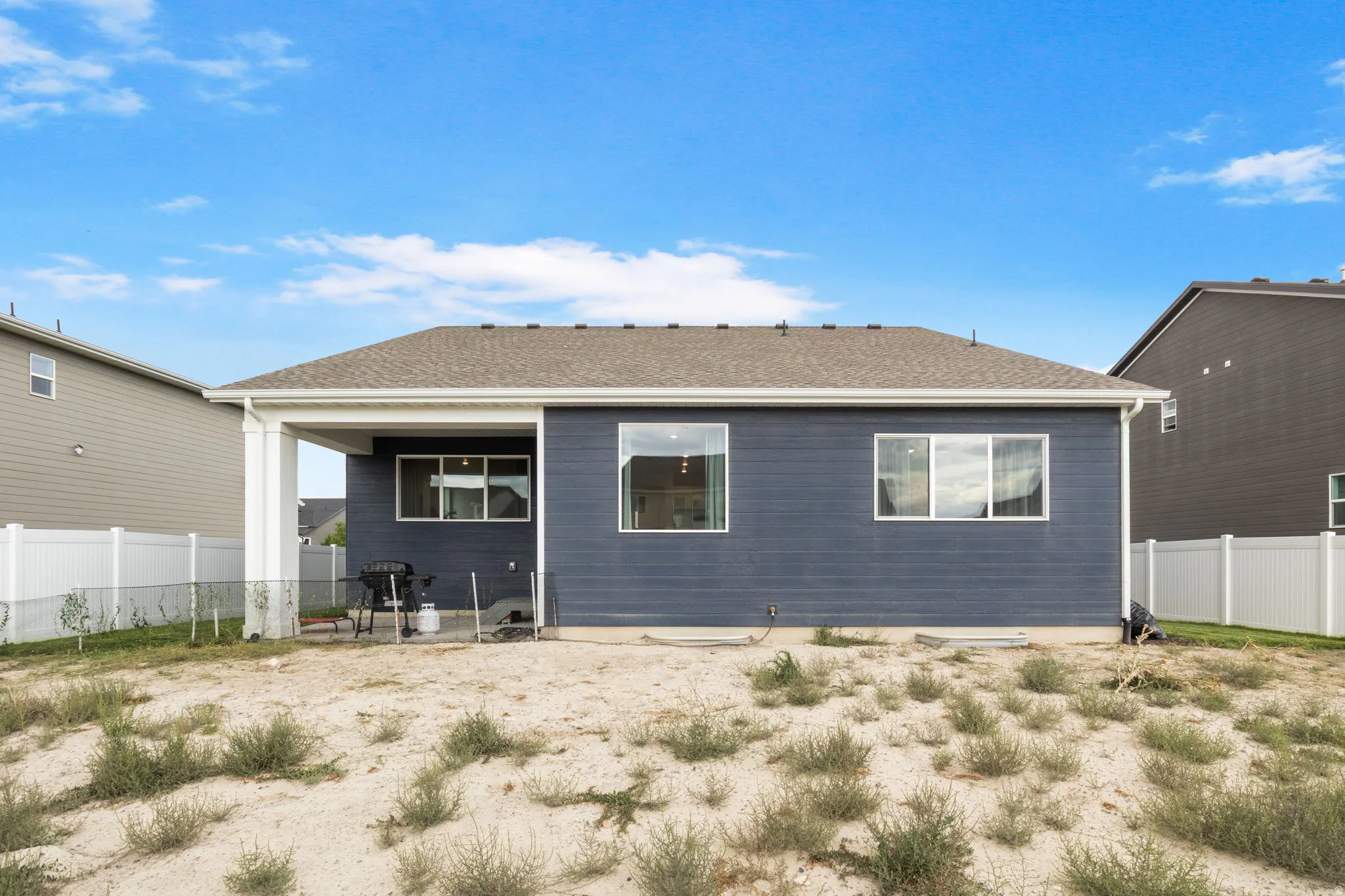 Rear exterior featuring dark blue siding, a covered patio, backyard will be grassed