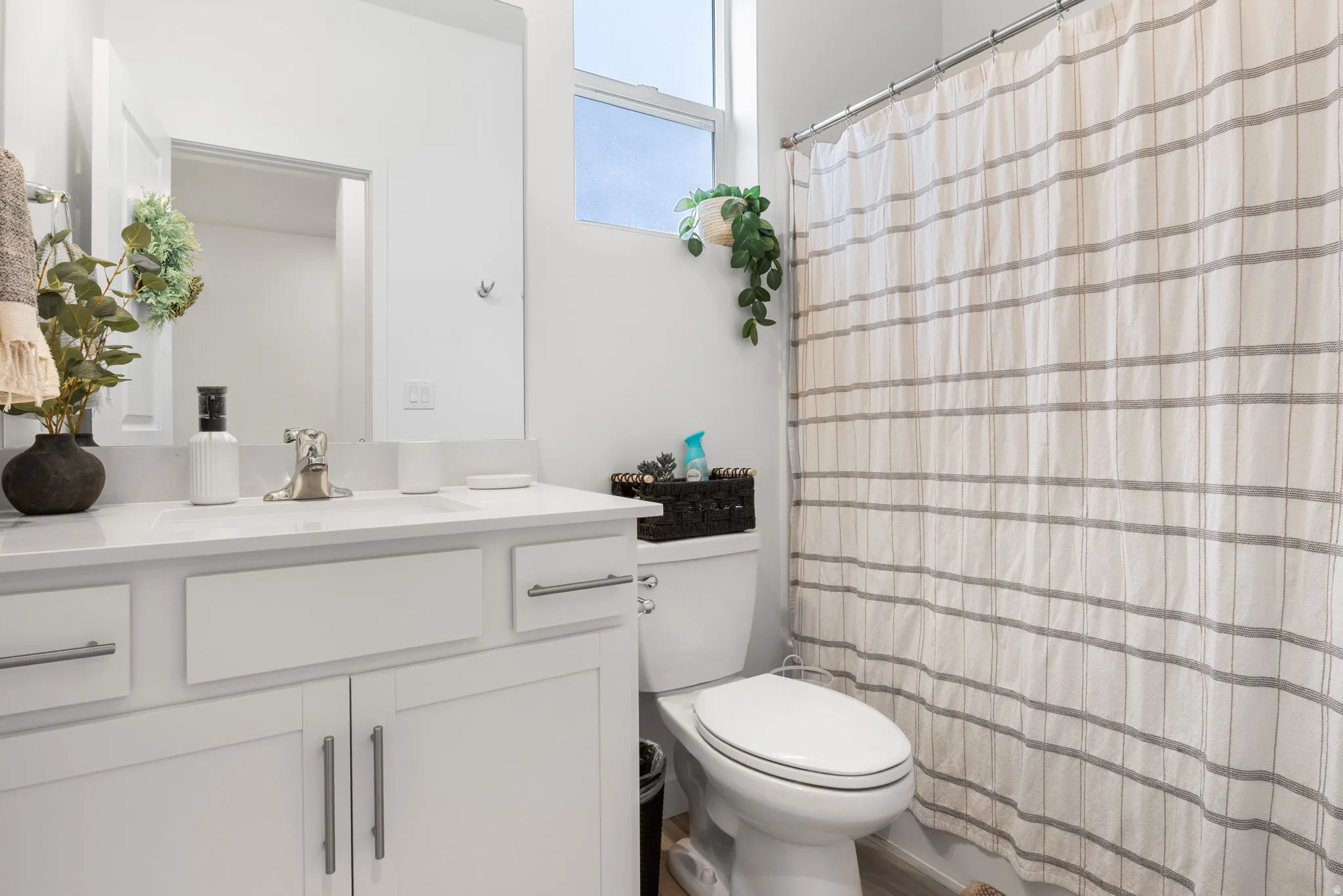Full guest bathroom with white vanity with a solid surface countertop, undermount sink, and brushed nickel faucet