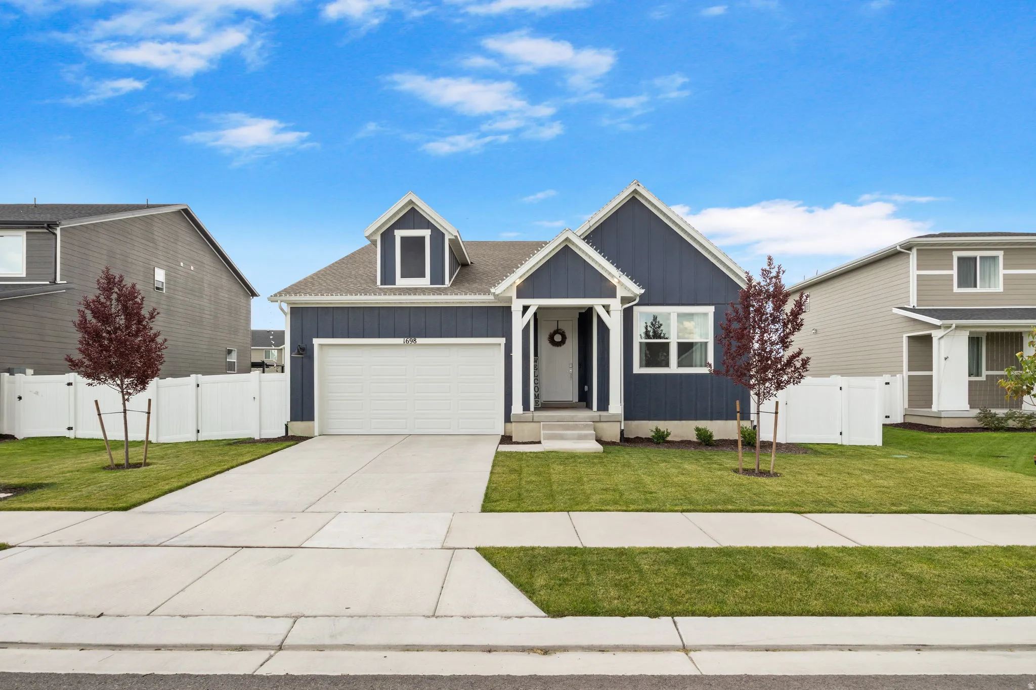 Contemporary exterior with blue vertical siding, white trim accents, an attached garage, a covered front porch, and a dormer window