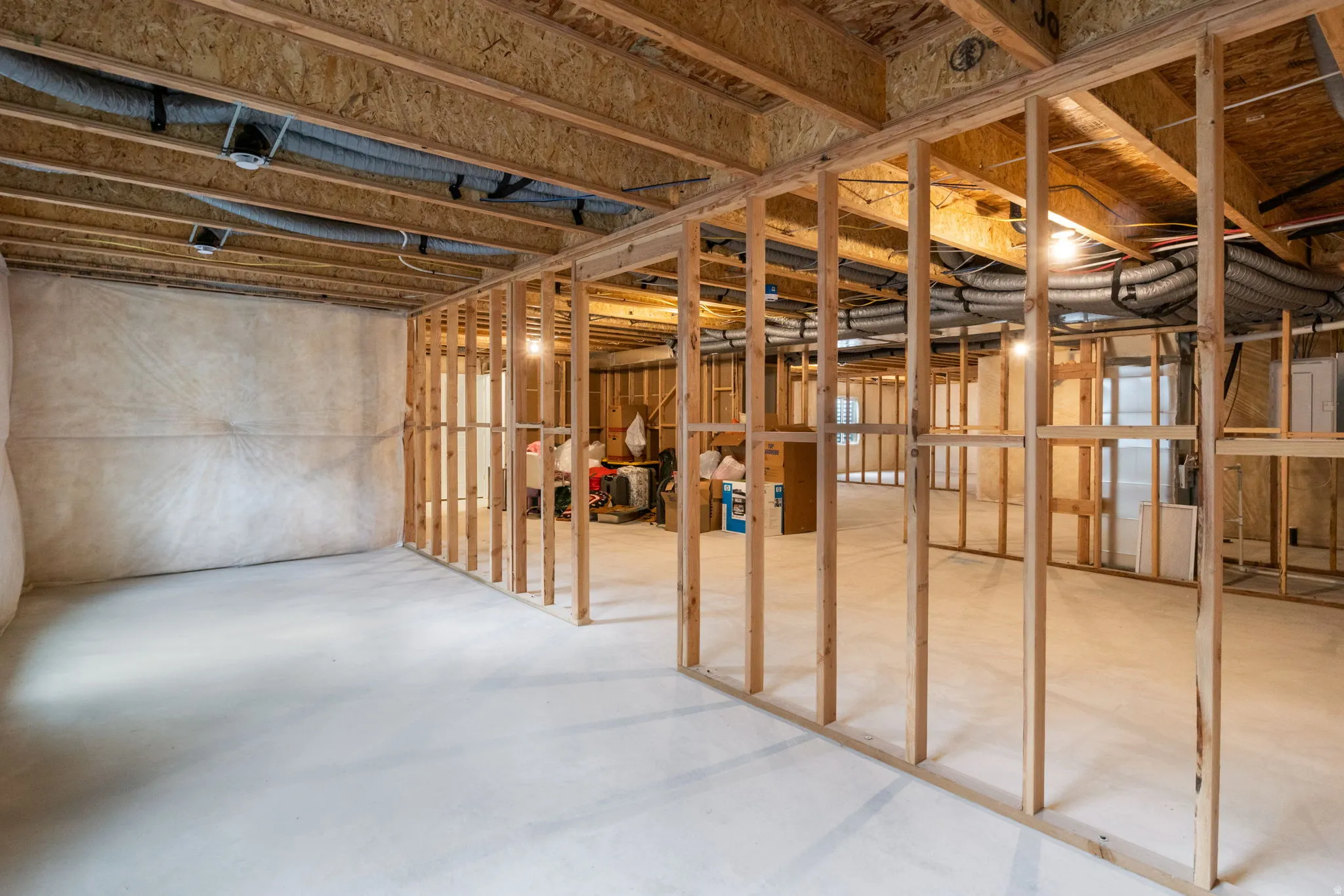 Expansive unfinished lower level with wood framing, concrete flooring.