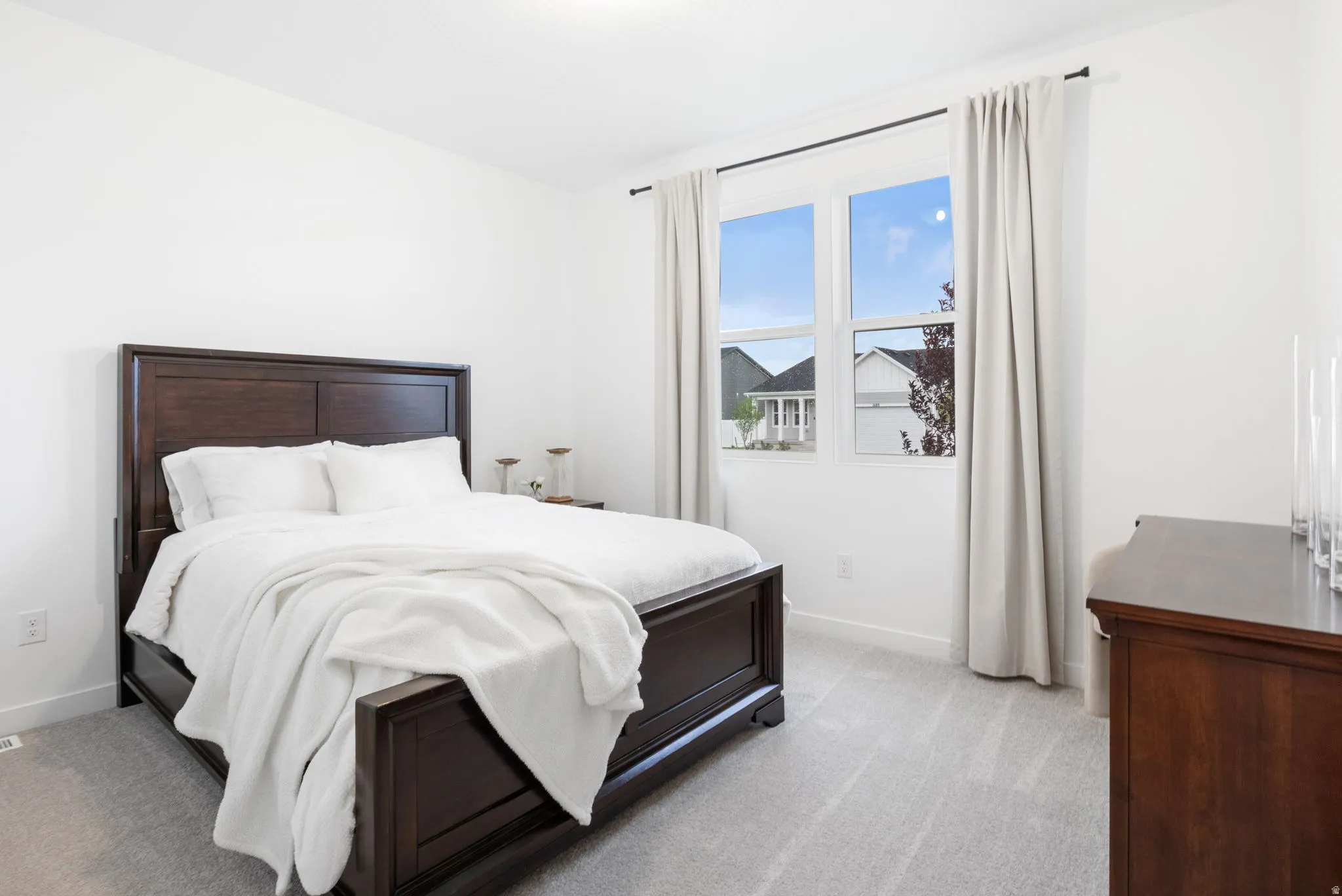 2nd bedroom with light grey carpeting, white painted walls, large window with white trim, and crown molding