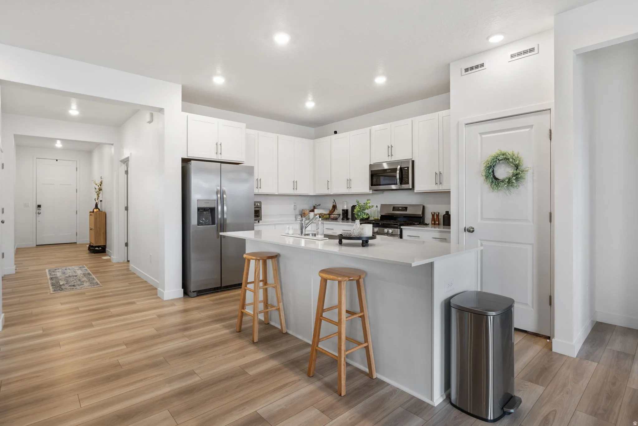 Kitchen with steel appliances, a large island with bar seating. LVP wood-finish flooring