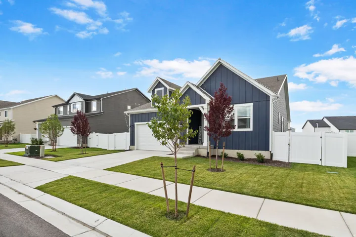 Like new home with attached two-car garage, concrete driveway, manicured lawn, and white privacy fencing