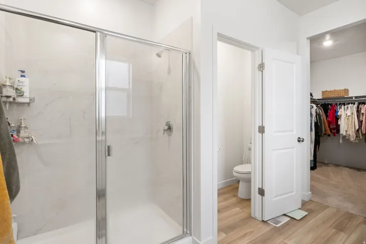 Large glass-enclosed shower with subway tile surround, separate water closet.
