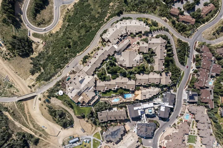 Aerial perspective highlighting the property's multiple buildings, surrounding natural terrain, and winding paved roads