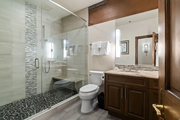 Glass-enclosed shower with a textured pebble floor and built-in bench