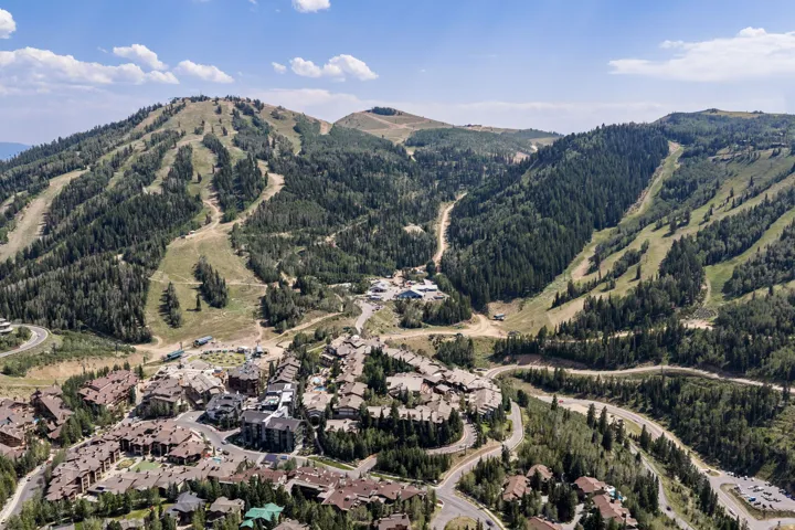 Aerial perspective showcasing a mountain community with surrounding ski slopes and dense tree coverage