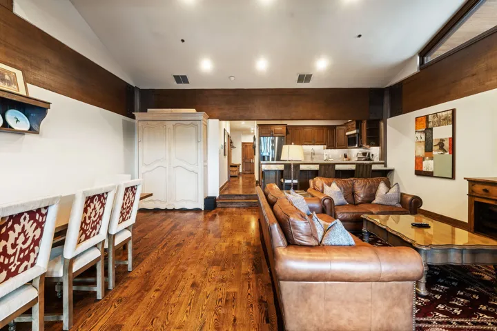 Hardwood flooring, recessed lighting, wood-finish accent beams, and a kitchen featuring wood cabinetry and a breakfast bar