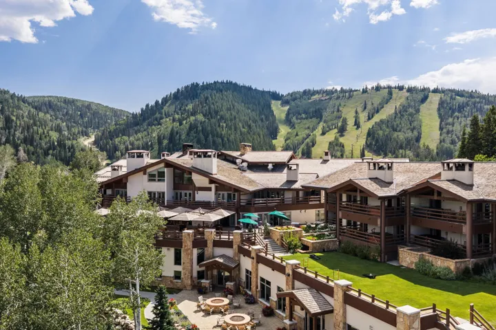 Multi-level structure with stone and wood-paneled exterior, multiple balconies, and a paved patio area
