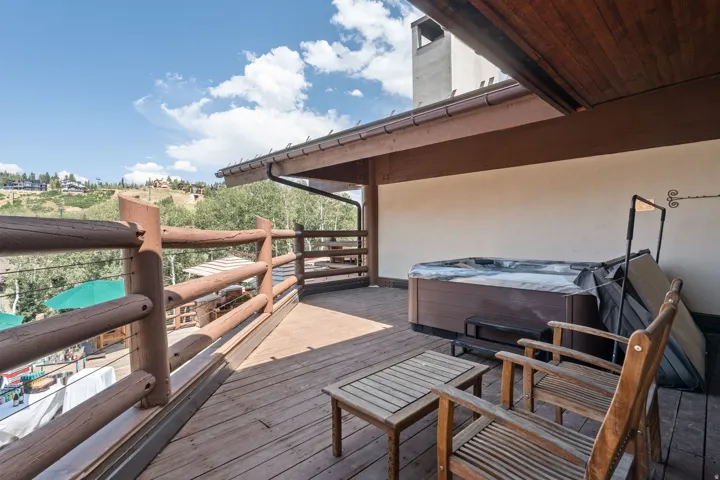 Expansive outdoor deck with wood railing, featuring a built-in hot tub