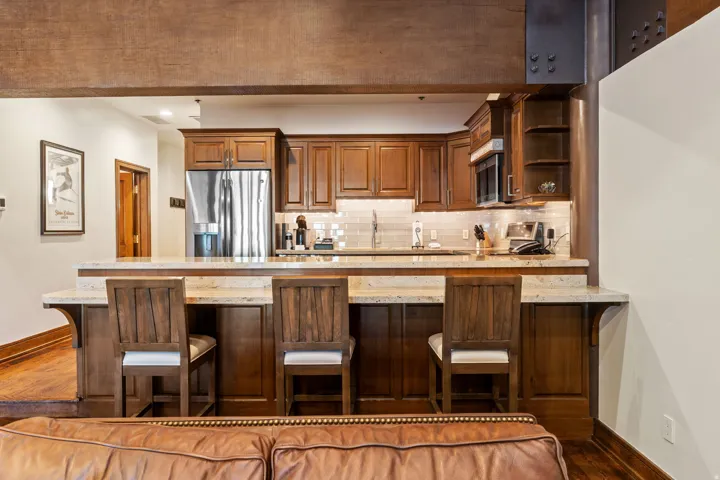 Kitchen featuring wood-finish cabinetry, stainless steel refrigerator, microwave, and light-toned countertops