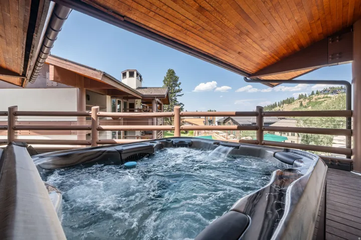 Outdoor deck with a built-in hot tub, wood-plank flooring, and a natural wood railing