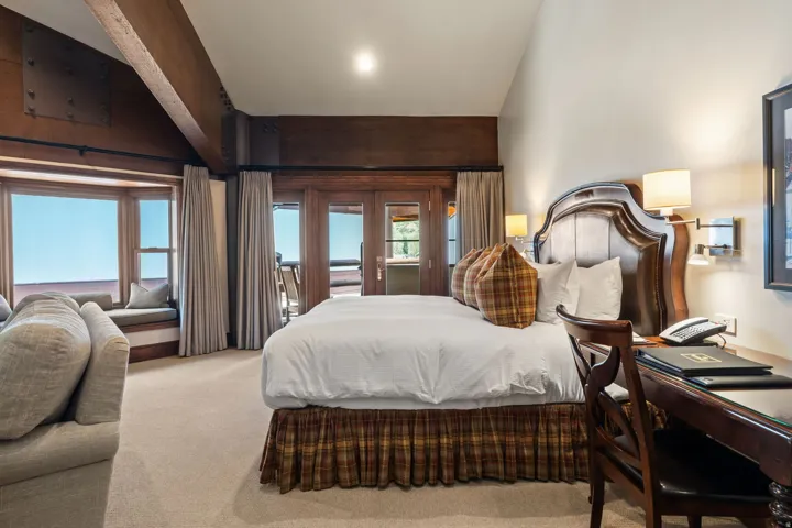 Spacious primary bedroom suite featuring rich wood-finish architectural details, recessed ceiling lighting, and expansive windows framing panoramic scenery