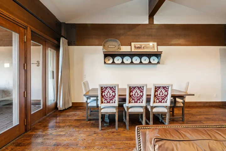 Vaulted ceiling with exposed wood beams, French doors with wood framing, and wood-finish flooring