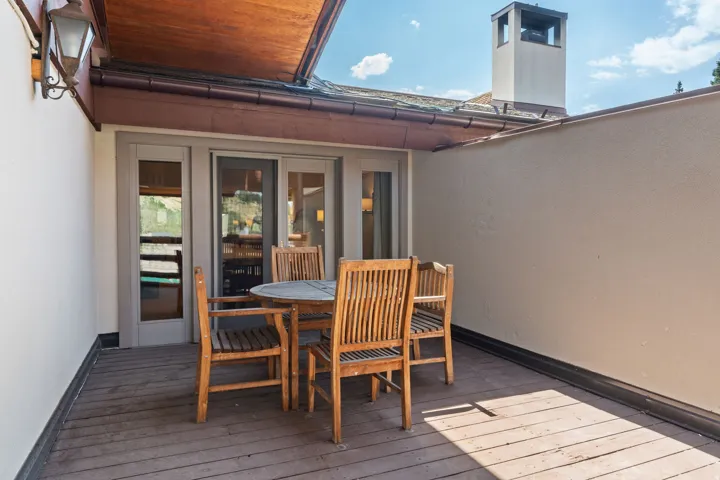 Private outdoor terrace featuring wood-finish decking, an attached exterior light fixture, and double glass-paneled doors