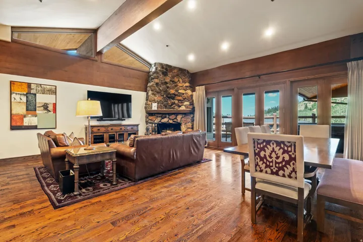Spacious great room showcasing soaring wood-beam ceilings, abundant recessed lighting, and hardwood flooring throughout