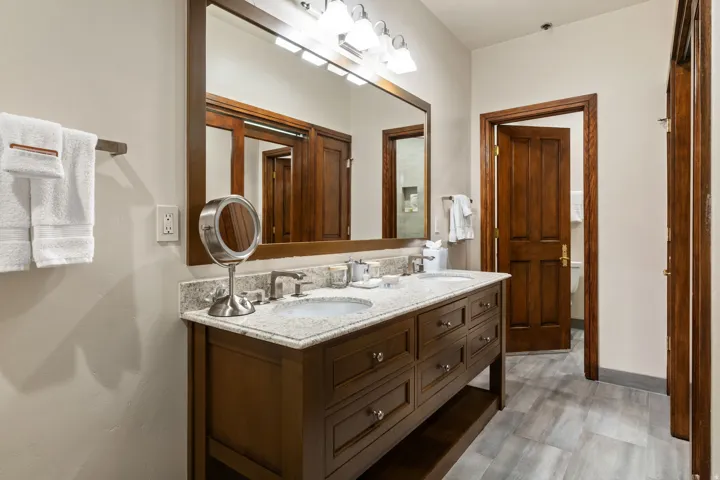 Dual vanity with stone countertop, integrated sinks, and wood-finish cabinetry