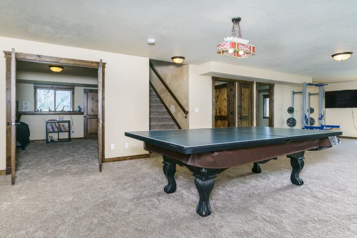 Carpeted flooring throughout, recessed lighting, and a visible staircase with wooden handrails