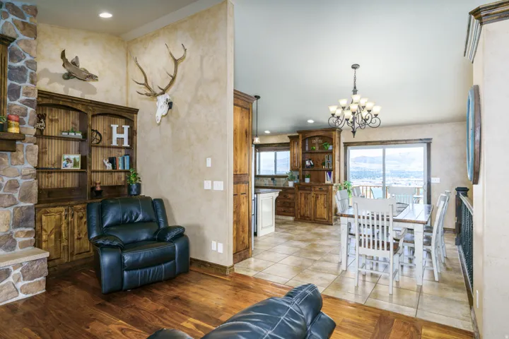 Stone-faced fireplace with hearth, custom built-in wooden shelving, wood-finish flooring, tiled flooring, and a multi-light chandelier