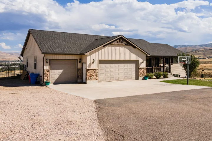 Exterior showcasing a multi-car garage, stone accent siding, and a covered porch