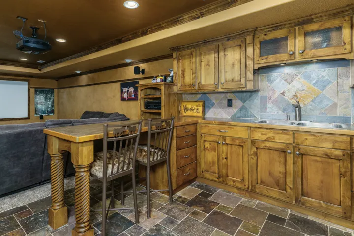 Custom wood cabinetry with glass-front uppers, dual stainless-steel sinks, and a multi-tone tile backsplash