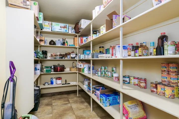 Walk-in pantry with extensive built-in shelving, durable tile flooring, and light-toned walls