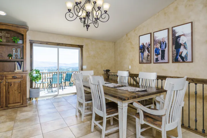 Built-in wood cabinetry with shelving, tiled flooring, sliding glass door leading to a balcony, and a multi-light chandelier