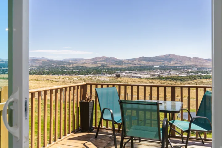 Expansive outdoor deck with wood railings, overlooking a distant cityscape and natural landscape