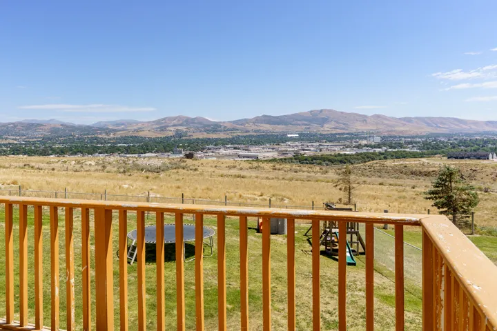 Wood-finish railing overlooking a expansive landscape with distant mountains