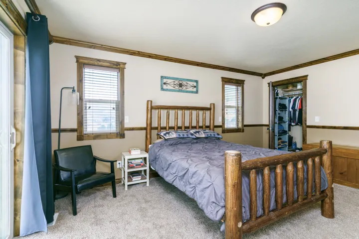 Wall-to-wall carpeting, two windows with blinds, wood trim detailing, and a built-in closet with shelving