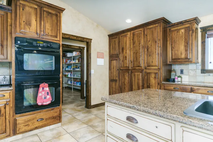 Spacious kitchen featuring custom wood cabinetry, granite countertops, stainless steel sink, and tile flooring