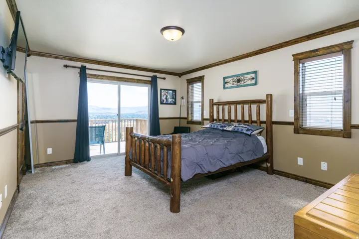 Plush carpet flooring, wood-framed windows, wood trim, ceiling-mounted light fixture, and sliding glass door to exterior deck