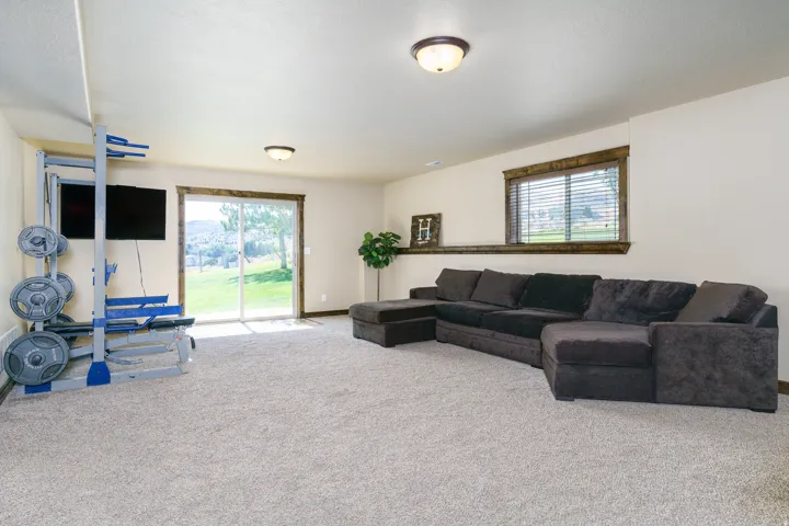 Recessed ceiling lighting, sliding glass door, neutral-toned carpeting, and wood-trim window