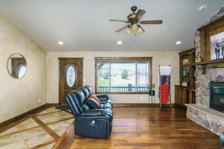 Hardwood flooring, recessed lighting, ceiling fan, stone-clad fireplace, and built-in cabinetry